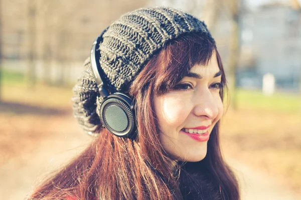Beautiful woman red coat listening music — Stock Photo, Image