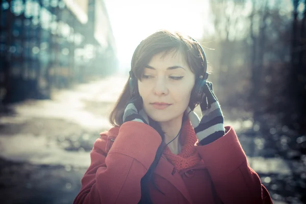 Belle femme manteau rouge écoute musique parc — Photo