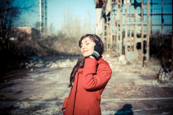 Beautiful woman red coat listening music park — Stock Photo, Image