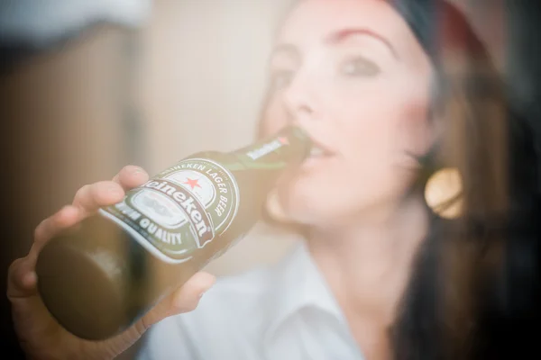 Женщина пьет Heineken бутылку пива 33 cl — стоковое фото