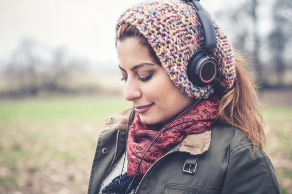 Mulher morena bonita ouvindo música com fones de ouvido — Fotografia de Stock