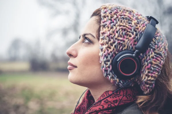 Schöne brünette Frau hört Musik mit Kopfhörern — Stockfoto