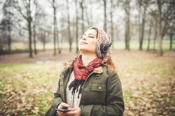 Schöne brünette Frau hört Musik mit Kopfhörern — Stockfoto