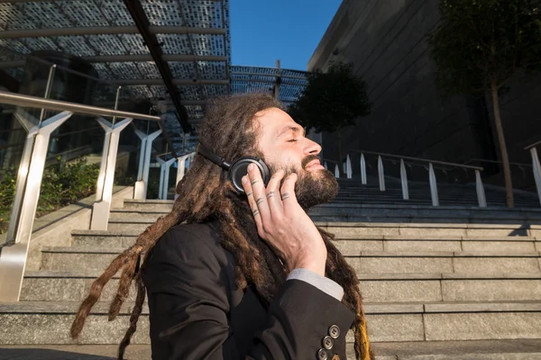 スタイリッシュなエレガントなドレッドヘアのビジネスマンは、音楽を聴く — ストック写真