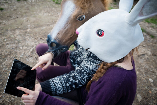 Young hipster cuople horse and rabbit mask using tablet