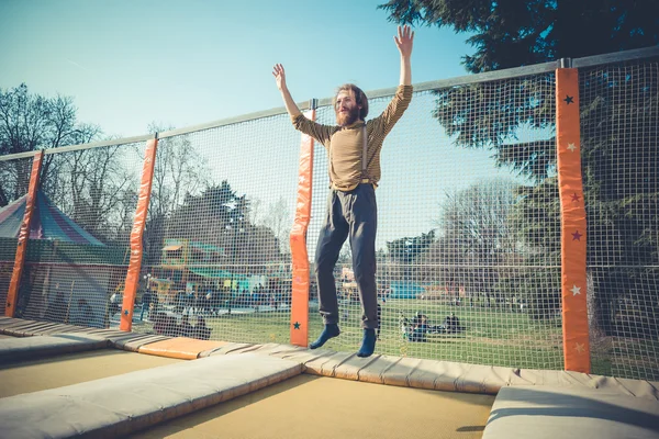 Uomo che salta sul trampolino al parco giochi — Foto Stock