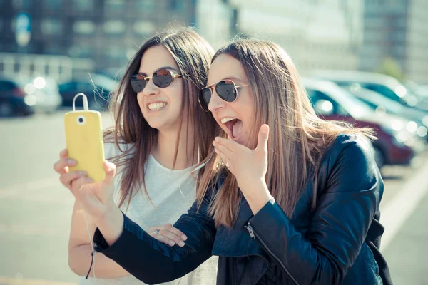 Två vackra unga kvinnor som använder smart telefon selfie — Stockfoto