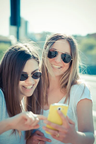 Duas belas mulheres jovens usando telefone inteligente — Fotografia de Stock