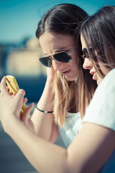 Twee mooie jonge vrouwen met behulp van slimme telefoon — Stockfoto