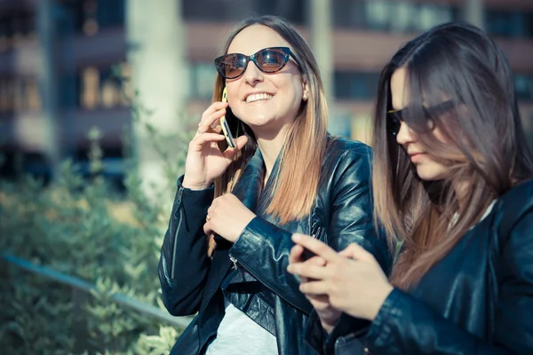 Två vackra unga kvinnor som använder smart telefon — Stockfoto