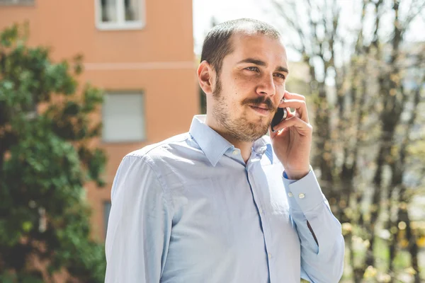 Elegante negocio multitarea multimedia hombre llamando con smartp —  Fotos de Stock