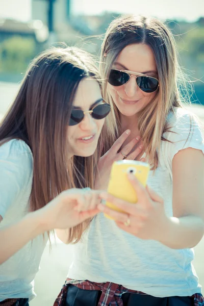 Två vackra unga kvinnor som använder smart telefon — Stockfoto