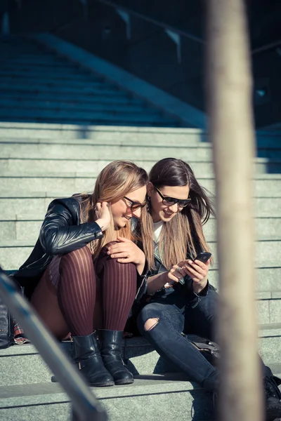 Two beautiful young women using smart phone — Stock Photo, Image
