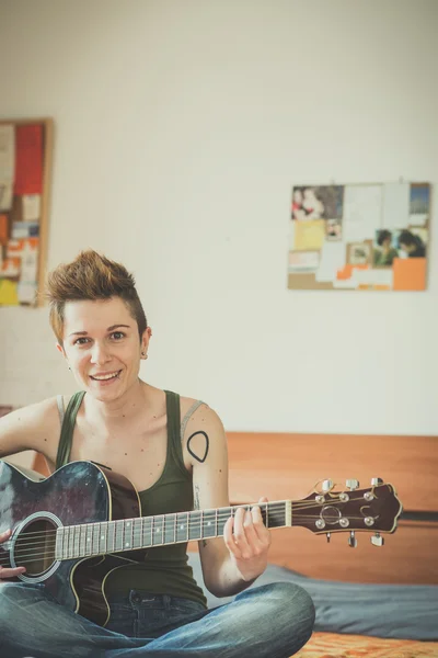 Jovem lésbica elegante cabelo estilo mulher tocando guitarra — Fotografia de Stock