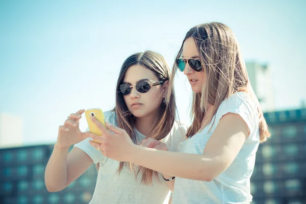 Två vackra unga kvinnor som använder smart telefon — Stockfoto