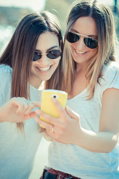 Iki güzel genç kadın akıllı telefon kullanma — Stok fotoğraf