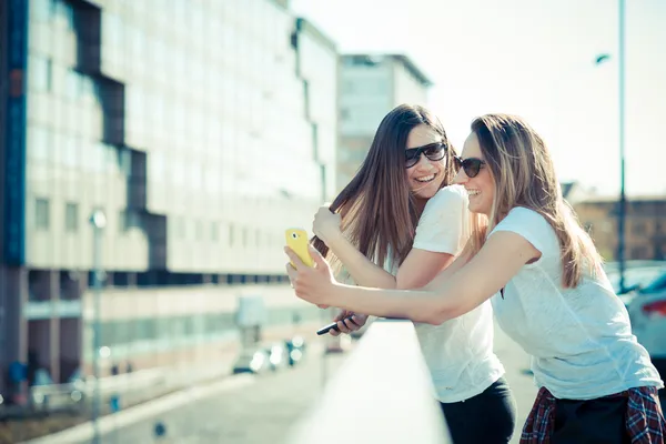 Two beautiful young women using smart phone — Stock Photo, Image