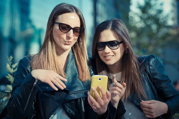 Två vackra unga kvinnor som använder smart telefon — Stockfoto