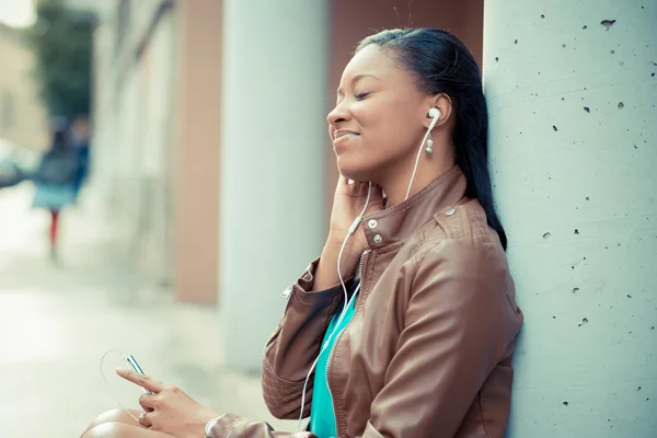 Mooie Afrikaanse jonge vrouw luisteren muziek oortelefoons — Stockfoto