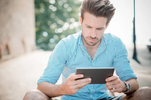 Joven guapo hipster hombre moderno utilizando tableta al aire libre — Foto de Stock