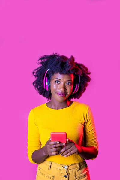 Νεαρή Μαύρη Γυναίκα Ακούει Μουσική Ασύρματα Ακουστικά Κρατώντας Smartphone Απομονωμένο — Φωτογραφία Αρχείου
