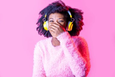 Genç siyah mutlu kadın gülerek müzik dinliyor kablosuz kulaklık takıyor izole bir arka plan