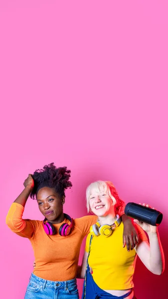 若い多様な黒と白人の女性屋内を保持する無線Bluetoothスピーカーダンス一緒に楽しい笑いの広告コピースペースを持っている — ストック写真