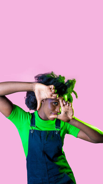 Young black woman focusing eye at camera through photo frame gesture cropping view isolated on pink copy space background