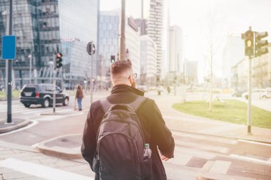 Arka manzara yetişkin adam sırt çantasıyla yürüyen şehir geri dönüyor iş şehri günbatımı