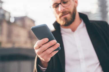 Sakallı genç adam akıllı telefon kullanarak başarılı bir iş çıkardı.