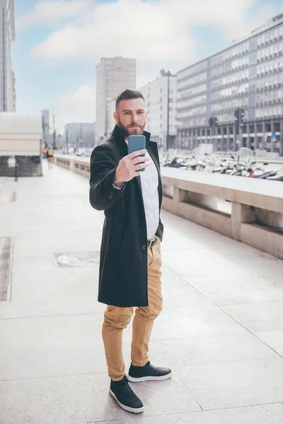 年轻的有胡子的高加索优雅男子在户外使用智能手机视频或自拍积极的微笑 — 图库照片