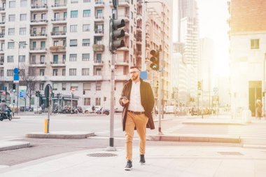 Kafkasyalı genç iş adamı akıllı telefon kullanarak dışarıda yürüyor. İnternet üzerinden 5G teknolojisi kullanıyor, video yayını izliyor ya da oyun oynuyor.