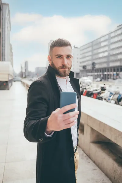 若いですひげを生やした白人男性屋外でスマートフォンを使用して自己紹介をしますソーシャルメディア — ストック写真
