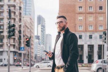 Genç, çağdaş, sakallı iş adamı akıllı telefon kullanıyor. Kendine güvenen ve sakin.