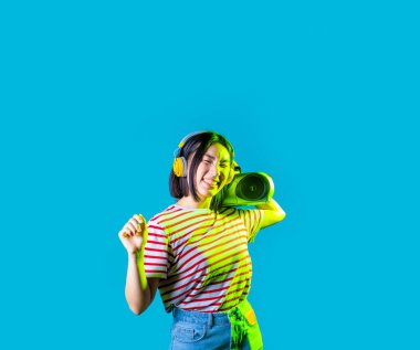 Genç Asyalı kadın dans ediyor, müzik kaseti dinliyor, elinde teyp var, kulaklık takıyor, özgürce gülümsüyor, mutlu, kırpılmış bayrak taşıyor. 