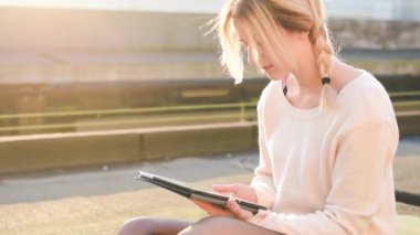 Dışarıdaki beyaz kadın tablet sörf ağı kullanıyor borsayı kontrol ediyor ve online alışveriş yapıyor.