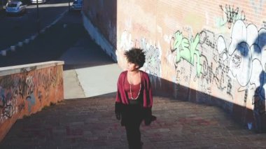 Genç siyahi kadın dışarıda yürüyor, tek başına gezmenin tadını çıkarıyor.