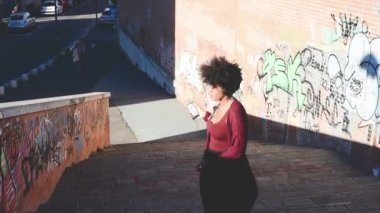 Genç siyahi kadın dans ediyor, müzik dinliyor, kulaklık takıyor, akıllı telefon eğleniyor.