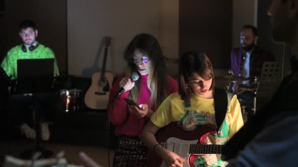 音楽バンドがレコーディングスタジオで演奏 女性歌手が歌詞を読むスマートフォン コンサート レコーディング 楽しいコンセプトを持つ — ストック動画