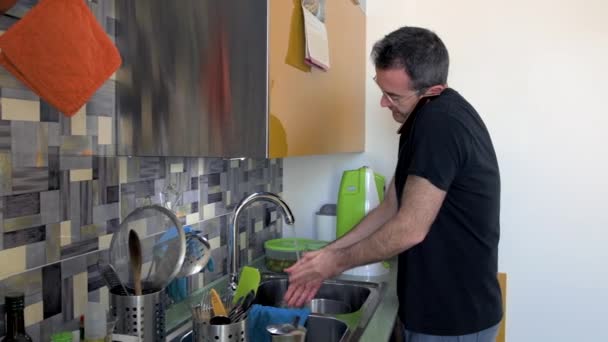 大人の男性屋内での家庭用洗濯機スマートフォンを話す料理 遠隔作業の概念 — ストック動画