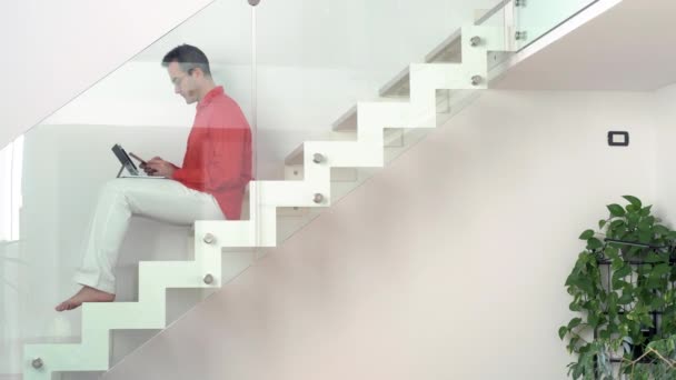 Alleinstehender Erwachsener Mann Hause Sitzt Mit Smartphone Und Tablet Treppenhaus — Stockvideo