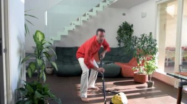 Evde tek başına oturan bir adam oturma odasının zeminini vakumla temizliyor. Temizlik günü, temizlik, temizlik, temizlik...