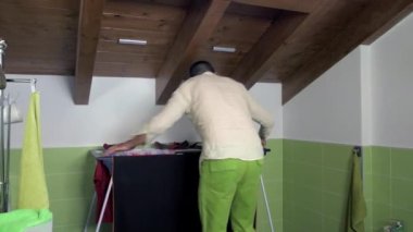 Evde yalnız yetişkin bir adam çamaşırlarını kurutuyor çamaşır atına asıyor ve kendini hazırlıyor. Hizmetçi, ev işi, temizlik konsepti.
