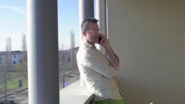 Yetişkin adam terasta esnek bir işçi akıllı telefondan konuşuyor uzaktan konuşma yapıyor - teknoloji, iletişim, iş konsepti