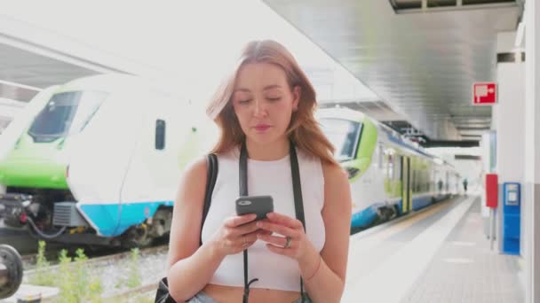 Mujer joven de cámara lenta usando un teléfono inteligente que mira la cámara positiva y confiable en el futuro — Vídeo de stock