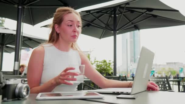 Junge Frau sitzt mit Computervideotelefonie im Freien — Stockvideo