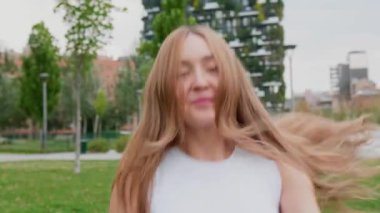 Ağır çekim beyaz kadın dışarıda dans ediyor kendini özgür hissediyor ve müzikten zevk alıyor.