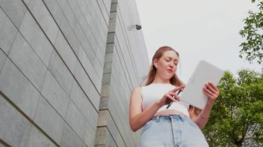 Yavaş çekim genç çoklu görev yapan kadın dışarıda iş görüşmesi akıllı telefon ve kulaklıkla tablet tutuyor.