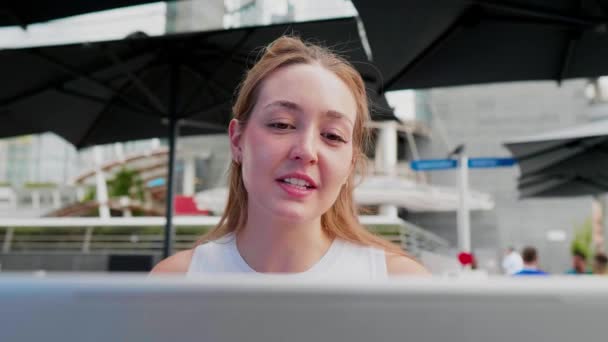 年轻的高加索女人在户外用电脑拍片 一边笑一边挥手致意 — 图库视频影像