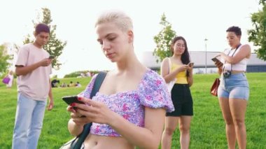 Genç mutlu beyaz kadın dışarıda akıllı telefon kullanıyor gülümsüyor, sohbet ediyor ya da internette sörf yapıyor.